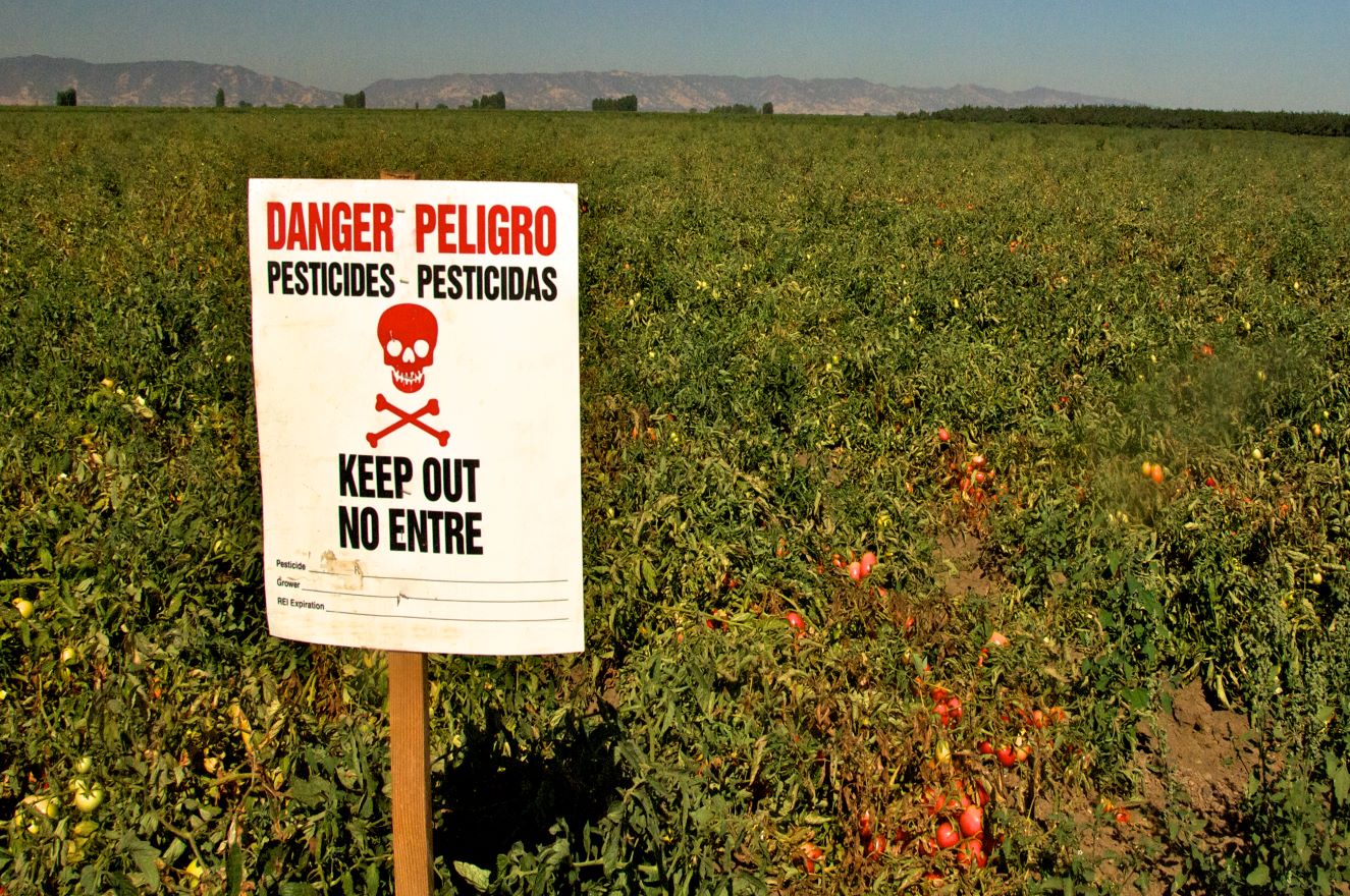 A sign in a field reading "danger, pesticides, keep out"
